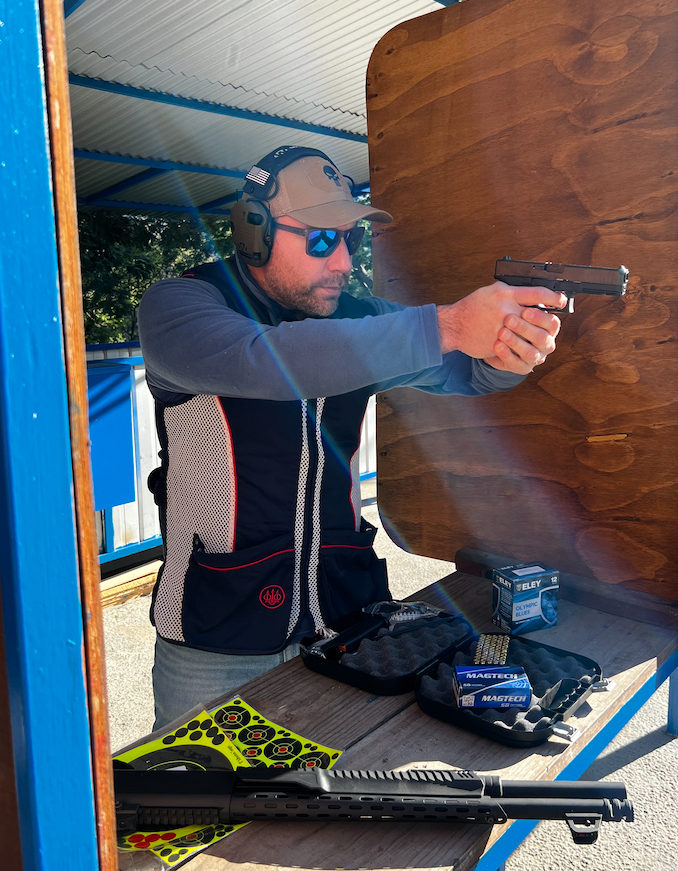 Tirador practicando con pistola en puesto de tiro techado
